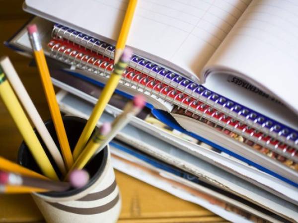 Stack of books or paperwork on desk. High angle view, pencils in holder in foreground.