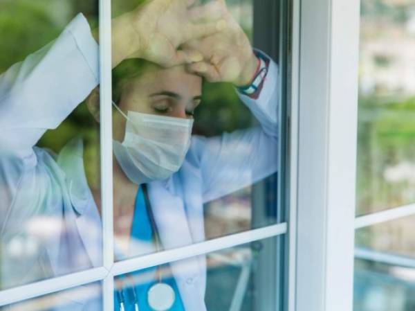 Worried female doctor looking through the hospital window