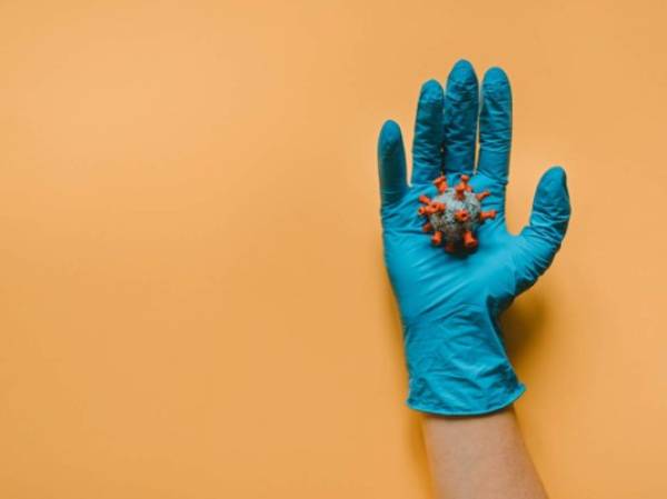 Hand with protect glove holding model Coronavirus on the background.