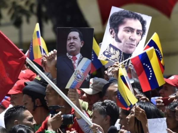 Government supporters carry images of late Venezuelan President Hugo Chavez (L) and Venezuelan Liberator Simon Bolivar during a rally in Caracas on the day of the installation of the Constituent Assembly on August 4, 2017.Venezuelan President Nicolas Maduro was set to install a powerful new assembly packed with his allies Friday, dismissing an international outcry and opposition protests saying he is burying democracy in his crisis-hit country. / AFP PHOTO / JUAN BARRETO