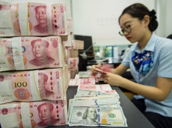 A Chinese bank employee counts 100-yuan notes and US dollar bills at a bank counter in Nantong in China's eastern Jiangsu province on August 28, 2019. - China's currency slid on August 26 to its weakest point in more than 11 years as concerns over the US trade war and the potential for global recession weighed on markets. (Photo by STR / AFP) / China OUT