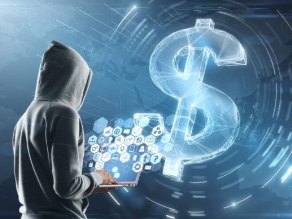 cyber attack concept with hacker in grey hoody with laptop and multimedia icons on screen. digital dollar sign background.