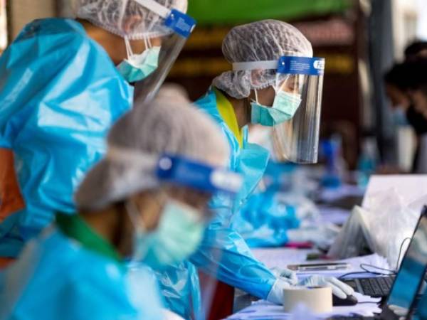 Medical workers take details from people, as hospitality and tourism workers are tested for the Covid-19 coronavirus on Khao San Road, in Bangkok on January 6, 2022. (Photo by Jack TAYLOR / AFP)