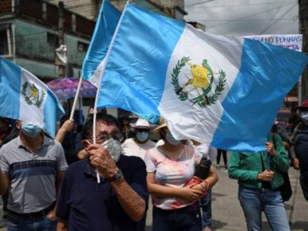 Demonstrators hold Guatemalan flags during a protest to demand the resignation of Guatemalan President Alejandro Giammattei and Guatemala's Attorney General Maria Consuelo Porras after Guatemala's Special Prosecutor against Impunity Juan Francisco Sandoval was dismissed, outside the Public Ministry's headquarters in Guatemala City on July 24, 2021. (Photo by Johan ORDONEZ / AFP)