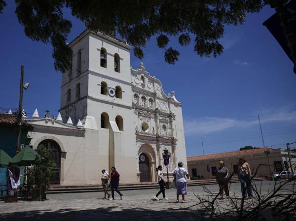 <i>Fotografía del 11 de abril de 2025 de personas caminando frente a la catedral de la Inmaculada Concepción en Comayagua (Honduras). En pleno corazón de Honduras, la ciudad de Comayagua guarda en lo alto un tesoro: un reloj en la torre del campanario que muchos aseguran ser el más antiguo de América, incluso del mundo, mientras que otros historiadores dudan de esos datos ante la falta de documentos que lo verifican. EFE/ Bienvenido Velasco</i>