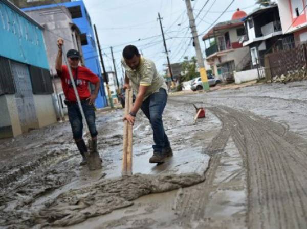 A man removes the mud left by the flooding after the rains related to the passage of Hurricane Maria, in Toa Baja, Puerto Rico, on September 22, 2017.Puerto Rico battled dangerous floods Friday after Hurricane Maria ravaged the island, as rescuers raced against time to reach residents trapped in their homes and the death toll climbed to 33. Puerto Rico Governor Ricardo Rossello called Maria the most devastating storm in a century after it destroyed the US territory's electricity and telecommunications infrastructure. / AFP PHOTO / HECTOR RETAMAL