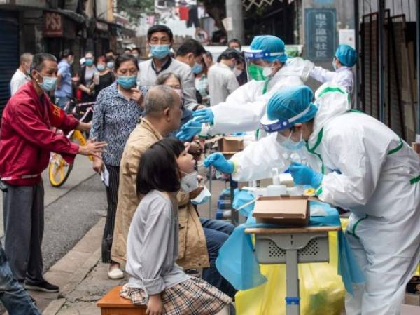 (FILES) This file photo taken on May 15, 2020 shows medical workers taking swab samples from residents to be tested for the COVID-19 coronavirus in a street in Wuhan in China's central Hubei province. - Chinese authorities have completed a mass coronavirus testing campaign in Wuhan, finding only 300 positive results among nearly 10 million people in the city where the pandemic began, local officials said on June 2, 2020. (Photo by STR / AFP) / China OUT