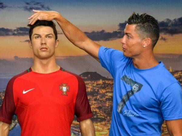 Portugese forward Cristiano Ronaldo poses next to a wax statue representing himself during a visit to the new location of the CR7 museum dedicated his professional career at Funchal, on the Portuguese island of Madeira on July 23, 2016. (Photo by JOANA SOUSA / AFP)