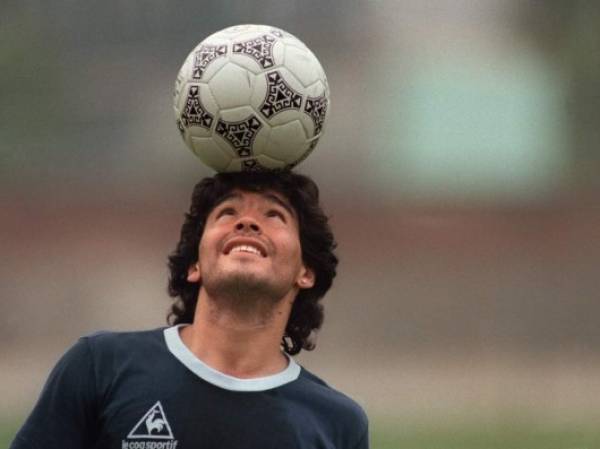 (FILES) In this file picture taken on May 22, 1986 Argentine football star Diego Maradona, wearing a diamond earring, balances a soccer ball on his head as he walks off the practice field following the national team's practice session in Mexico City. - Argentine football legend Diego Maradona turns 60 on October 30, 2020. (Photo by JORGE DURAN / AFP)