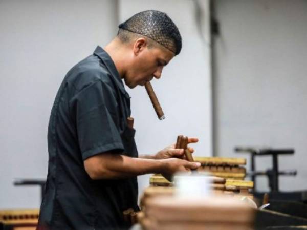 A worker smokes a cigar at a cigar factory in Esteli, Nicaragua on May 17, 2019. - Nicaragua is consolidating as the largest exporter of cigars to the US, an industry which was born in the fertile lands of Esteli. (Photo by INTI OCON / AFP)