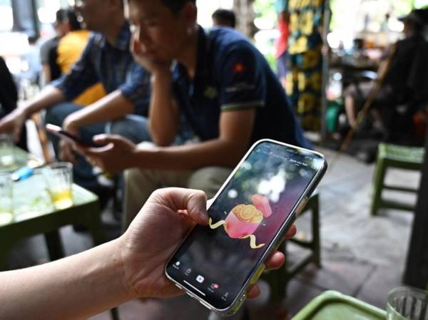 <i>Un hombre mira la plataforma de redes sociales TikTok en su teléfono móvil en Hanoi el 6 de octubre de 2023. FOTO HANÓI, VIETNAM</i>