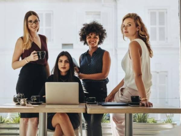 Portrait of four successful young businesswomen together in office. Group of multi-ethnic businesswomen looking at camera.