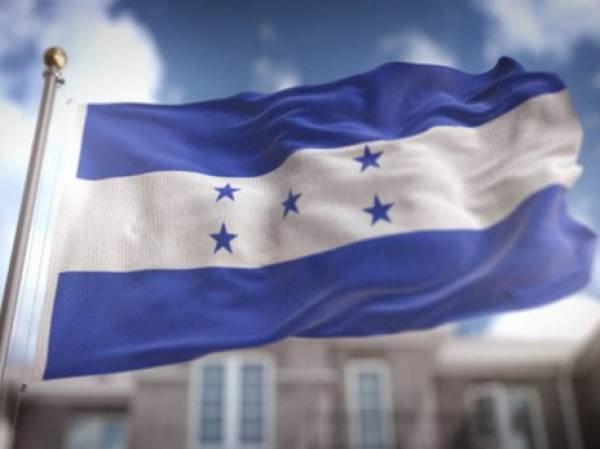 A member of the opposition holds up the national flag of Honduras while participating in a caravan along Morazan Boulevard to demand the resignation of President Juan Orlando Hernandez, in Tegucigalpa, on July 15, 2020. - The opposition accuses the government of corruption in the purchase of seven mobile hospitals, equipment and biosecurity material to fight the novel Coronavirus, which so far has left more than 800 dead and 29,106 infected. (Photo by ORLANDO SIERRA / AFP)