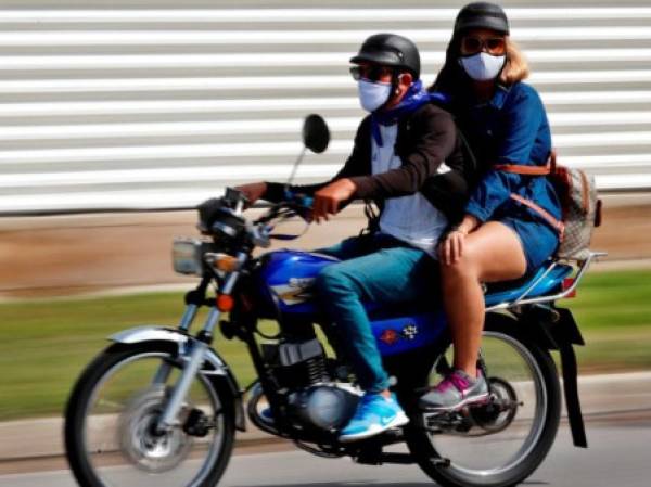 Dos personas con tapabocas se movilizan en una moto, este lunes en La Habana (Cuba). EFE/Ernesto Mastrascusa