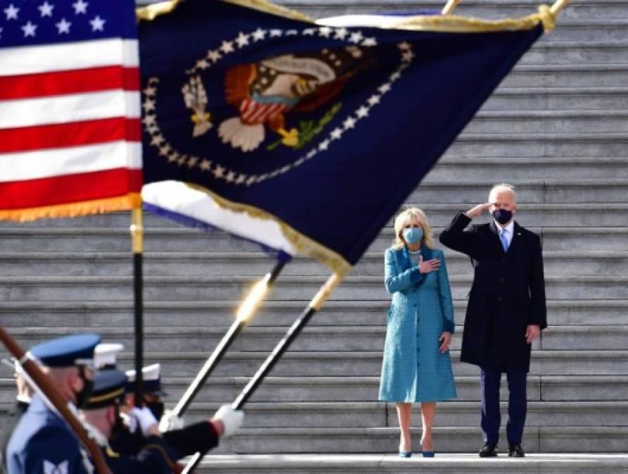 El presidente estadounidense Joe Biden saluda cuando la primera dama Jill Biden pone su mano en su corazón mientras revisan la preparación de las tropas militares en un pase en revisión en los escalones este del Capitolio de los EE. UU. En Washington, DC, el 20 de enero de 2021, después de ser juró en el Capitolio de los Estados Unidos. (Foto de David Tulis / POOL / AFP)