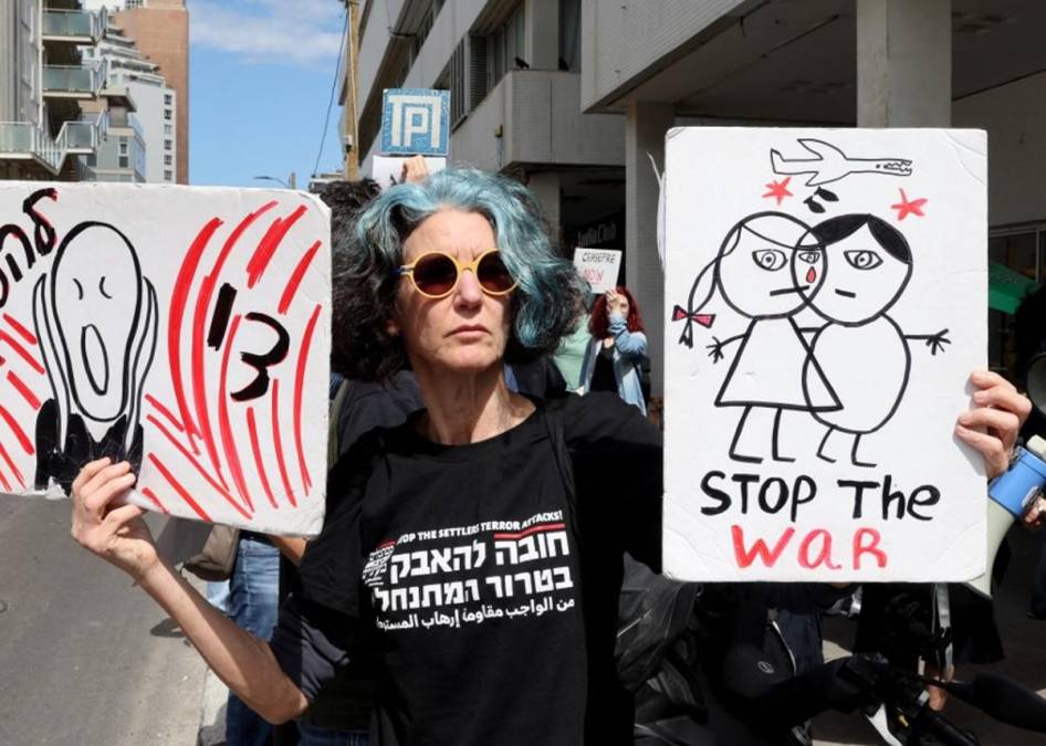 <i>Una mujer levanta pancartas mientras ciudadanos estadounidenses e israelíes se reúnen frente a la sucursal de la embajada de Estados Unidos en Tel Aviv para exigir que Estados Unidos deje de armar a Israel y ponga fin a la guerra en la Franja de Gaza, el 8 de marzo de 2024. FOTO JACK GUEZ / AFP</i>