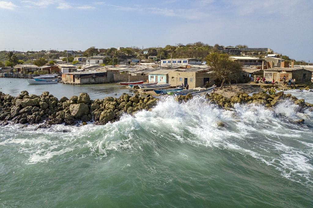 <i>Vista aérea de casas afectadas por el aumento del nivel del mar en la Isla Tierra Bomba, Cartagena, Colombia, tomada el 24 de febrero de 2024. Cada año el nivel del mar sube y se traga la bahía de Cartagena a cuentagotas. Un cementerio arrastrado por las olas muestra los efectos del calentamiento global en la ciudad más turística de Colombia, que podría quedar parcialmente bajo el agua en este siglo. (Foto de Luis ACOSTA/AFP)</i>