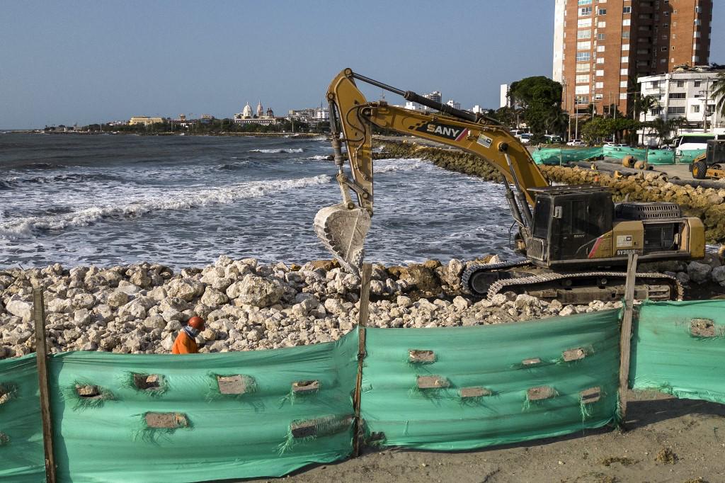 <i>Operadores trabajan con maquinaria pesada en la costa de Cartagena, Colombia, el 23 de febrero de 2024. Cada año el nivel del mar sube y se traga la bahía de Cartagena a cuentagotas. Un cementerio arrastrado por las olas muestra los efectos del calentamiento global en la ciudad más turística de Colombia, que podría quedar parcialmente bajo el agua en este siglo. (Foto de Luis ACOSTA/AFP)</i>