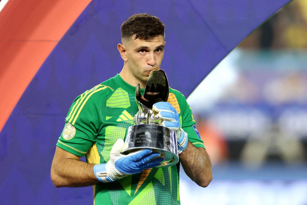 <i>El portero argentino #23 Emiliano Martínez besa el trofeo al mejor portero del torneo al final del partido final de fútbol de la Copa América Conmebol 2024 entre Argentina y Colombia en el Hard Rock Stadium, en Miami, Florida, el 14 de julio de 2024.CHARLY TRIBALLEAU / AFP</i> <i>El portero argentino #23 Emiliano Martínez besa el trofeo al mejor portero del torneo al final del partido final de fútbol de la Copa América Conmebol 2024 entre Argentina y Colombia en el Hard Rock Stadium, en Miami, Florida, el 14 de julio de 2024.CHARLY TRIBALLEAU / AFP</i>