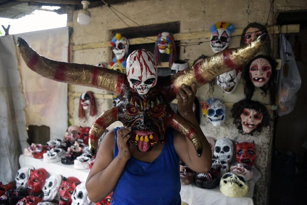 <i>La artesana Fermina López posa para una foto con una máscara de diablo para usar en el festival anual de Los Agüizotes y posa para una foto en su taller en la comunidad indígena de Monimbo en Masaya, Nicaragua (Foto de OSWALDO RIVAS/AFP)</i>