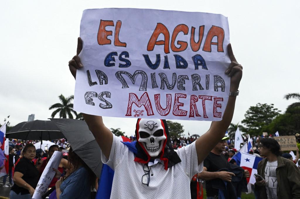 <i>Un manifestante sostiene un cartel que dice El agua es vida, la minería es muerte durante una protesta contra el contrato gubernamental con la empresa minera canadiense First Quantum -y su filial Minera Panamá- en la ciudad de Panamá, Panamá, el 26 de octubre de 2023. (Foto de LUIS ACOSTA/AFP)</i>