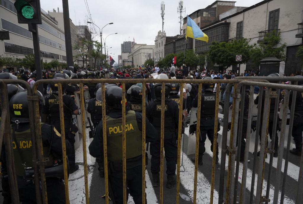 Miembros de la policía peruana montan guardia mientras los opositores del expresidente peruano Pedro Castillo celebran frente al edificio del Congreso en Lima, el 7 de diciembre de 2022. (Foto de Cris BOURONCLE / AFP)