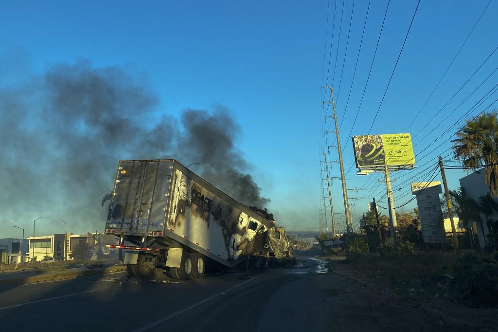 <i>Se ve un camión en llamas al otro lado de la calle durante una operación para arrestar al hijo de Joaquín “El Chapo” Guzmán, Ovidio Guzmán, en Culiacán, estado de Sinaloa, México, el 5 de enero de 2023. - Se reportaron tiroteos intensos y quema de vehículos el jueves. en la ciudad mexicana de Culiacán (noroeste) tras un operativo en el que fue detenido Ovidio Guzmán, hijo del narcotraficante preso Joaquín “El Chapo” Guzmán, dijeron autoridades mexicanas. (Foto por Marcos Vizcarra / AFP)</i>